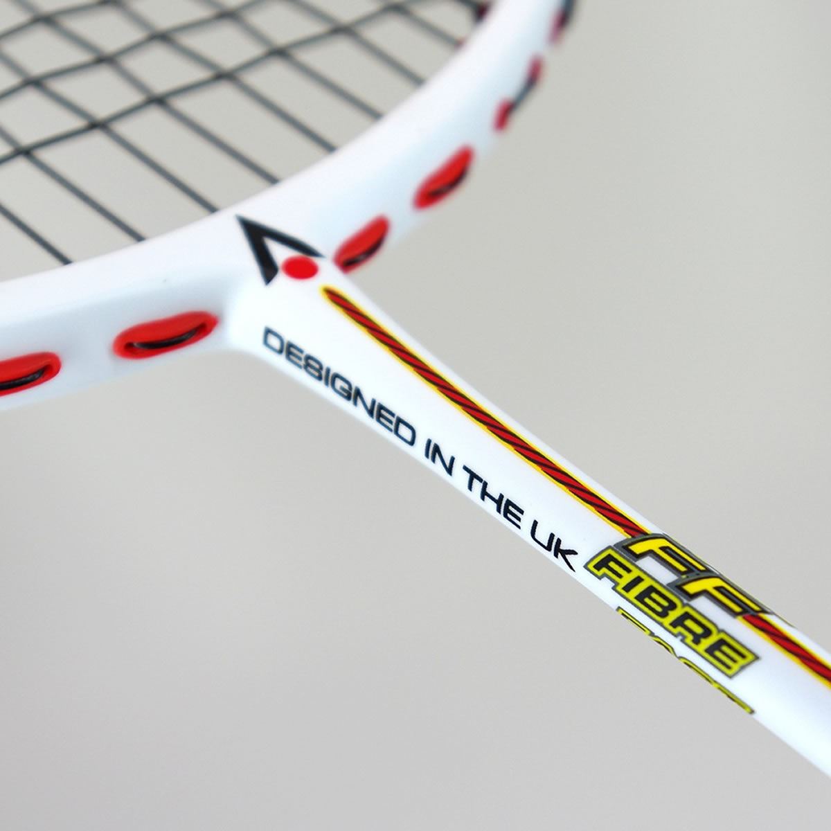 Close-up image of a Karakal Black Zone Lite Fast Fibre (FF) Graphite Badminton Racket - White, featuring red accents. The text "Designed in the UK" and "FF Fibre" is printed on the shaft, highlighting its lightweight speed capabilities. The partially visible strings and frame make it ideal for intermediate players seeking improved agility.