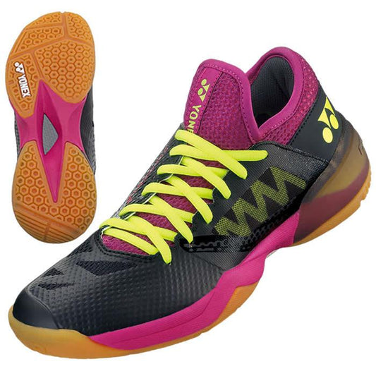 The Yonex Power Cushion Comfort Z2 Women's Badminton Shoes showcase a dynamic design featuring a 3D Power Graphite Drive. They have a black base accented with neon yellow laces and purple and pink details. Their orange sole includes hexagonal patterns for improved traction, while the Power Cushion+ offers exceptional comfort. The shoes are adorned with the Yonex logo on the side and tongue.