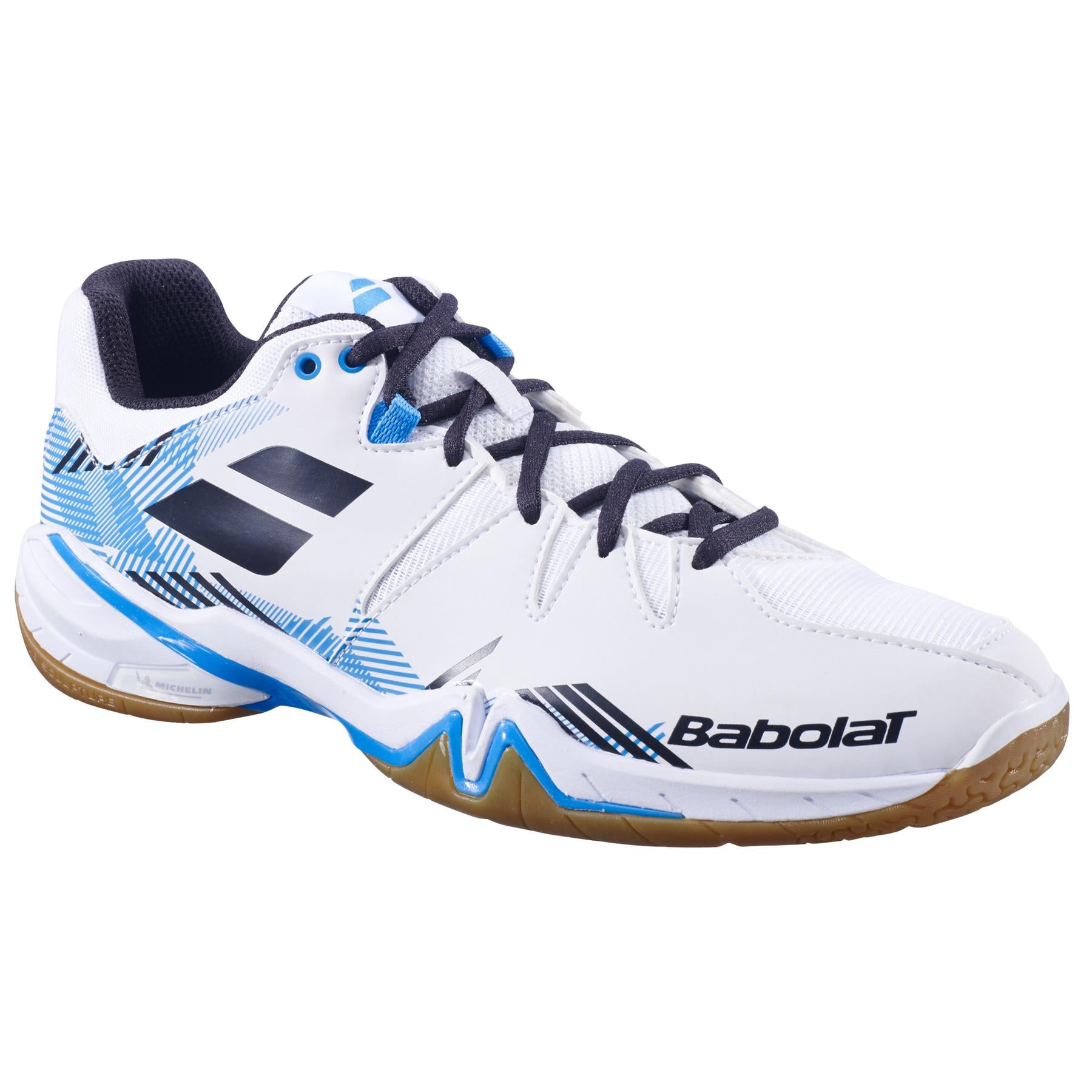 A white and black Babolat Shadow Spirit men's badminton shoe with brown soles and Ortholite Die Cut insoles. The shoe includes blue geometric patterns and the Babolat logo on the side for a stylish yet supportive appearance.