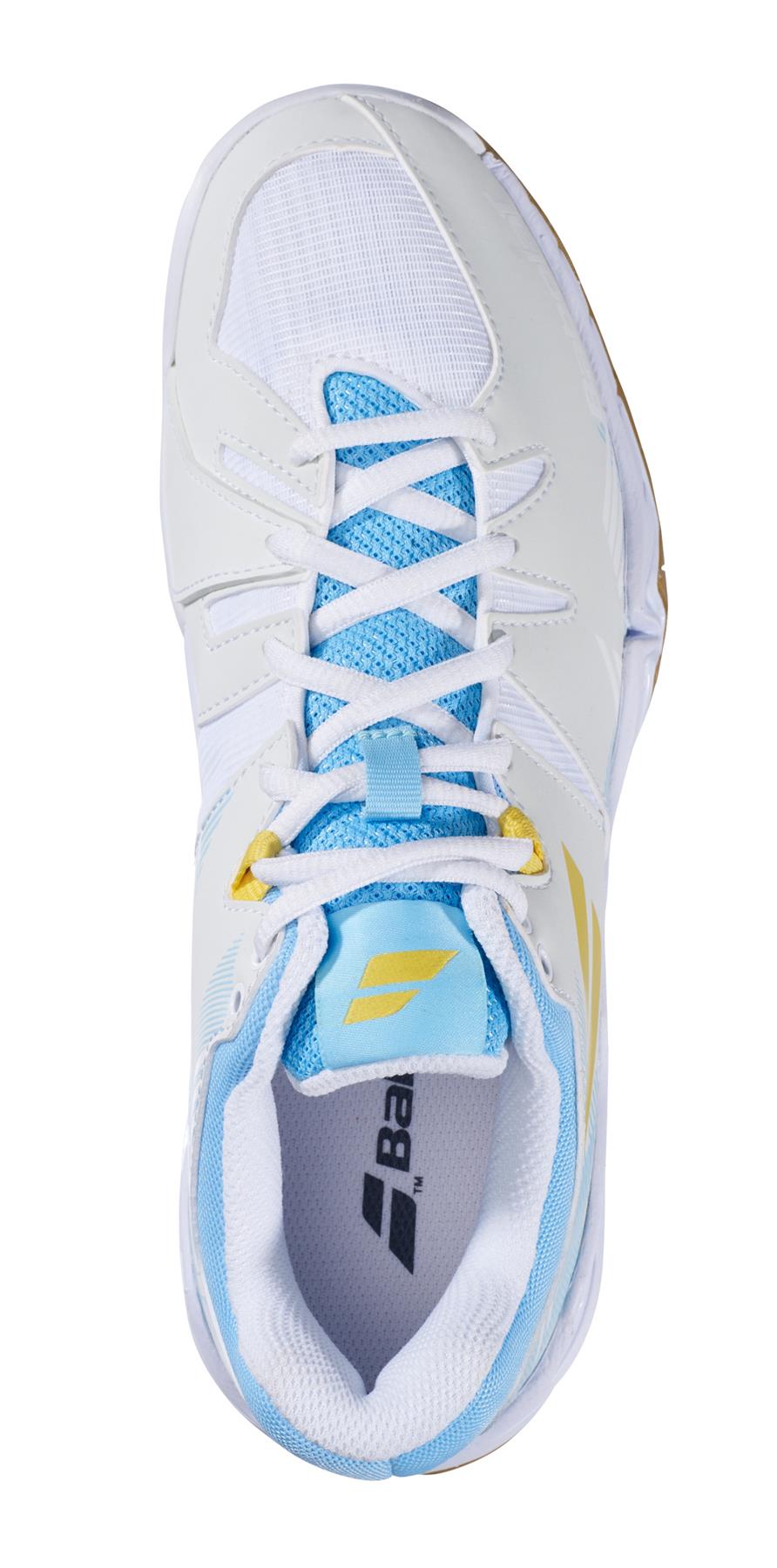 A top view of the Babolat Shadow Spirit 2023 women's badminton shoe in white and light blue, highlighted with yellow accents. This shoe is ideal for badminton enthusiasts, featuring a mesh upper and a thick sole. The brand's logo is prominently displayed in blue and gold on both the tongue and side, complemented by OrthoLite® Die Cut for enhanced comfort.