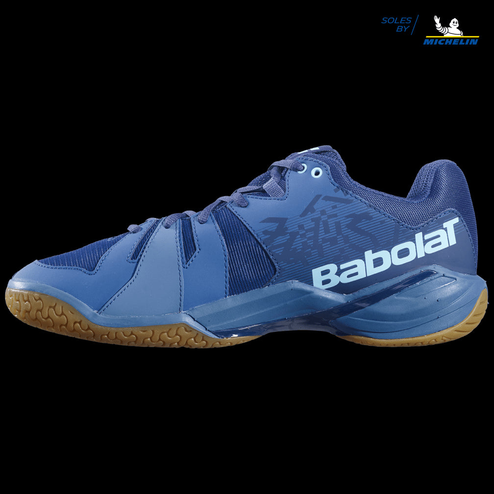 The Babolat Shadow Spirit Badminton Shoes in Dark Blue feature a textured brown Michelin rubber sole, providing durability and grip similar to other shoes in the Babolat Shadow Spirit series. Their sleek design, with a prominent logo and a combination of synthetic and mesh materials, offers ultimate comfort and support on the court.