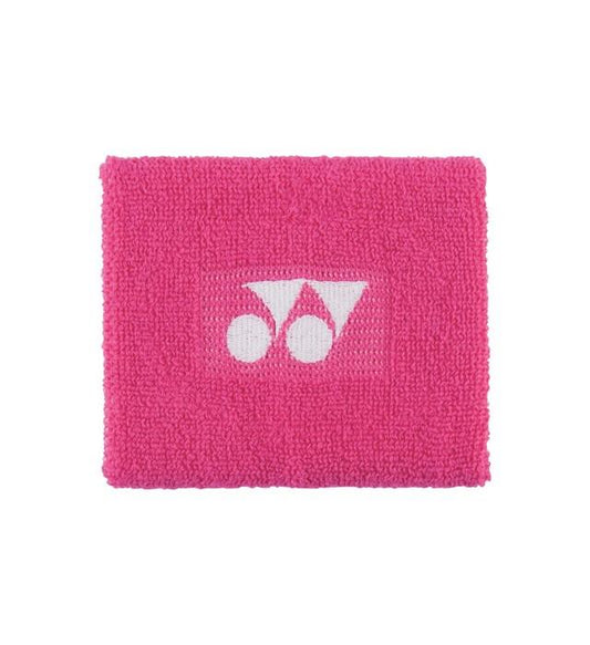 The Yonex Antibacterial Sweat Wristband in pink features a textured surface adorned with a white Yonex logo at the center, encircled by geometric shapes, set against a plain white background. This accessory is both stylish and practical due to its antibacterial properties.