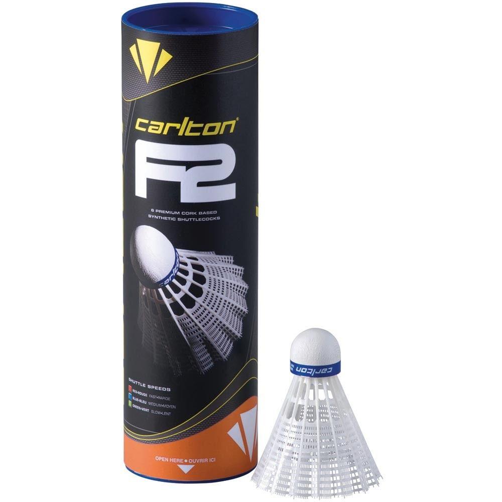 A tube of Carlton F2 Ti White Medium Badminton Nylon Shuttles is positioned upright beside a single shuttlecock. The packaging features black with yellow and blue accents, highlighting its speed variations and natural cork base for enhanced performance.