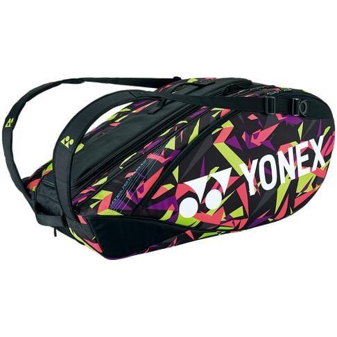 The Yonex 92226EX 6 Piece Pro Racket Bag - Smash Pink showcases a vibrant geometric design in pink, green, and yellow against a sleek black background. The bold Yonex logo is prominently displayed on the side of this racket bag. It includes multiple compartments and shoulder straps for easy carrying.