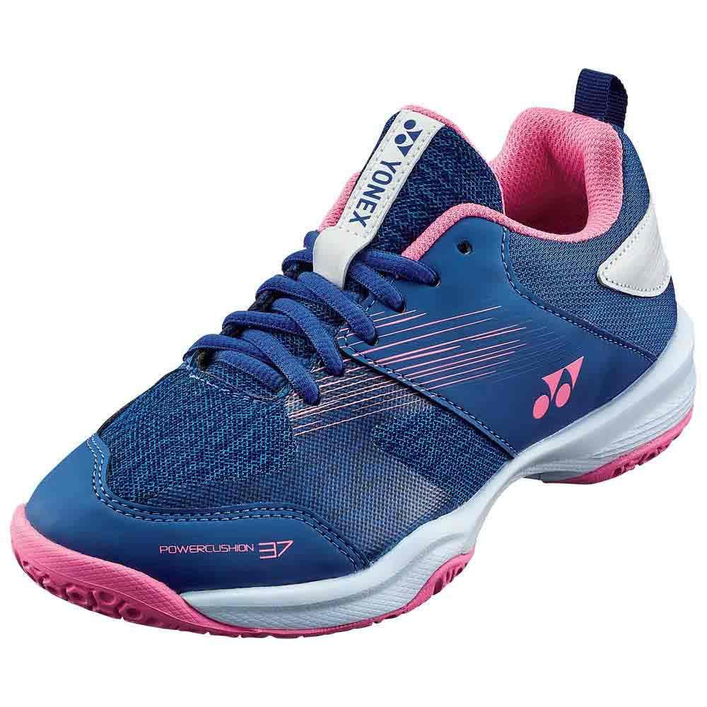 The Yonex Power Cushion 37 Women's Badminton Shoe, in a navy blue and pink color scheme, showcases white details and features the "Yonex" label on the tongue. It is equipped with a textured Power Cushion sole incorporating Hexagrip technology for enhanced grip, along with a logo on the side.