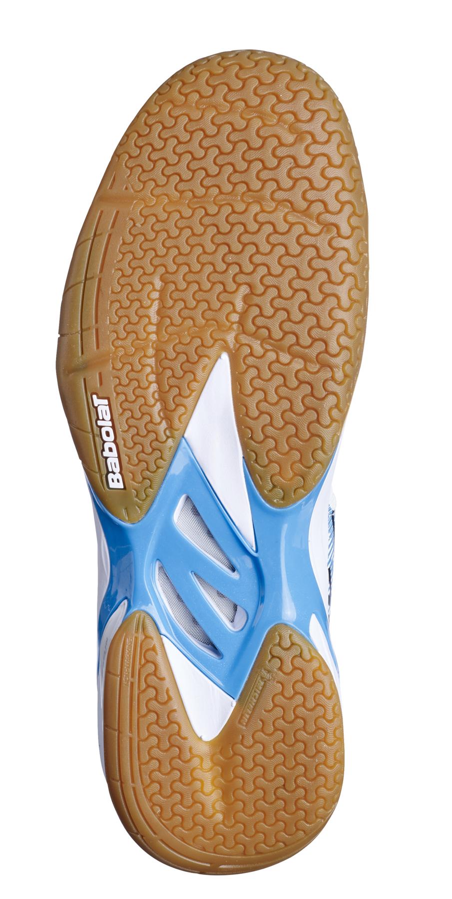 The image showcases the sole of a Babolat Shadow Spirit Men's Badminton Shoe with a herringbone pattern. With shades of blue and a brown rubber outsole, the "Babolat" branding stands out. The shoe's supportive design incorporates Ortholite Die Cut technology to boost comfort and performance on the court.