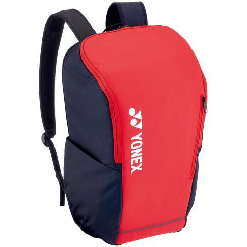 Introducing the Yonex 42312SEX Team Backpack in Scarlet, a dynamic red and black design with a large front pocket and the Yonex logo in white on the side. Equipped with adjustable shoulder straps, this versatile backpack is perfect for racket sports enthusiasts, featuring a main compartment covered by an elegant scarlet top flap.