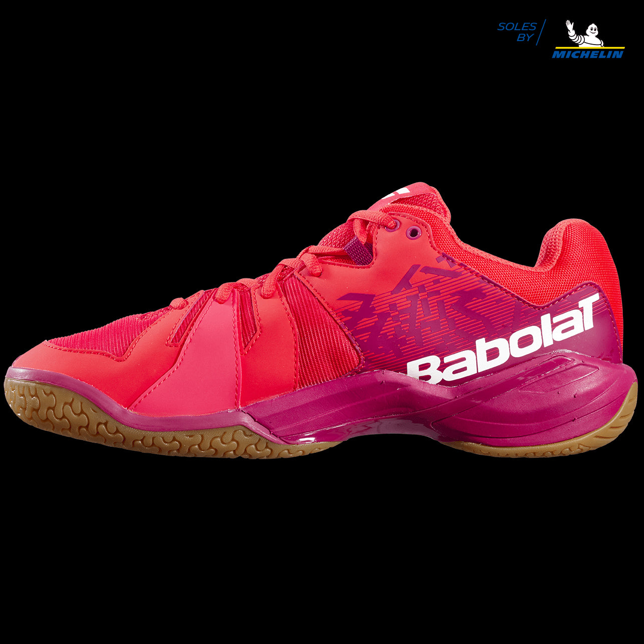 The Babolat Shadow Spirit Men's Badminton Shoes in a striking Cherry Tomato hue exhibit a sleek, aerodynamic design set against a black backdrop. Equipped with a gripsole made from Michelin rubber, these shoes deliver outstanding performance on the court.