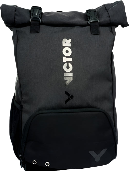 The Victor 9101 Rucksack Badminton Bag - Black by Victor showcases a roll-top design with "VICTOR" and the brand logo in white on the front. It includes a zippered front pocket with grommet details, generous compartments for shoes and rackets, as well as two adjustable clasps at the top for secure closure.