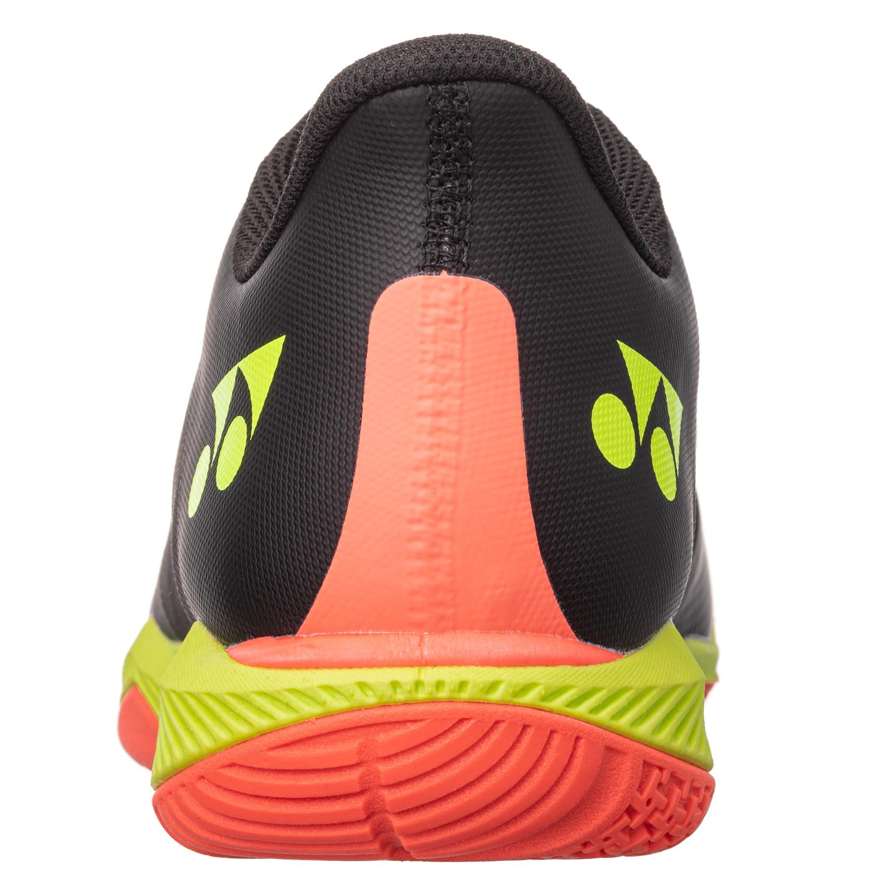 The image captures the rear view of the Yonex Power Cushion Comfort Z3 Mens Badminton Shoes in black. It features a bright orange heel and a neon yellow sole, with a patterned texture showcasing small yellow logos near the heel. Enhanced by Yonex's renowned Power Cushion technology for optimal performance and Feather Bounce Foam for added comfort, these shoes are designed to excel on the badminton court.