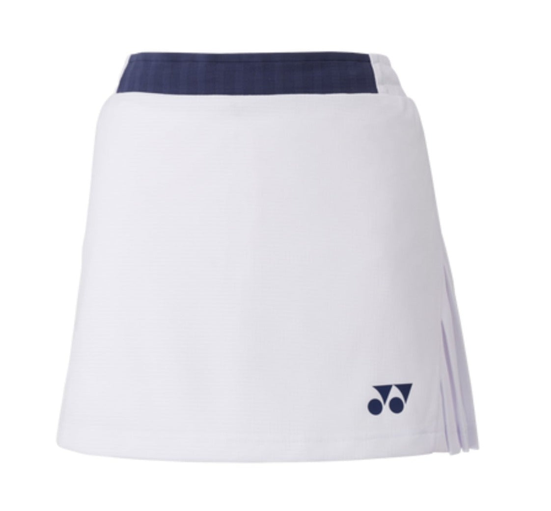 The Yonex 26094 Women's Skort - White is a chic tennis skirt featuring a dark blue waistband and stylish pleats on one side. It is adorned with a small logo in the bottom corner and includes UV reduction to provide extra protection for sunny matches.