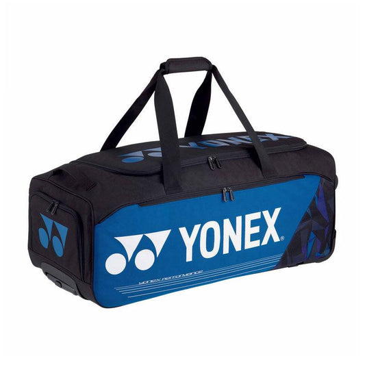 The Yonex 92232EX Pro Trolley Bag - Fine Blue by Yonex showcases a vibrant blue and black design featuring a white logo, making it perfect for tournament players. It includes a roomy main compartment for efficient gear organization, multiple smaller compartments, and dual black top handles for effortless transportation.