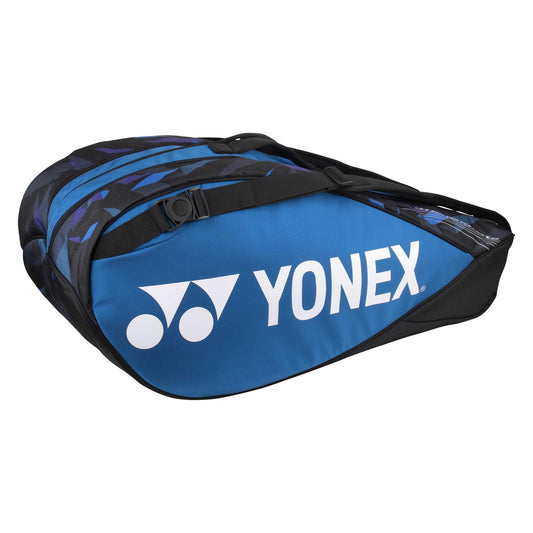 The Yonex 6 Piece Pro Badminton Racket Bag 92226 in Fine Blue features striking black and blue geometric patterns. It includes several compartments, such as an integrated shoe pocket, to ensure you're ready for your match. The Yonex logo is prominently displayed on the side.