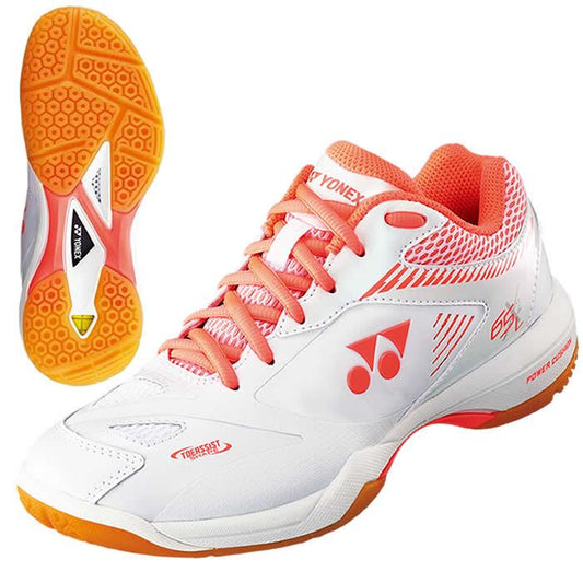 The Yonex Power Cushion 65 X2 Women's Badminton Shoes in white feature a vibrant orange design with a distinct sole pattern. They are embellished with a sports logo on the side, come equipped with orange laces, and include an advanced shock absorption system. Additionally, these shoes have textured accents and a sole that ensures superior grip.