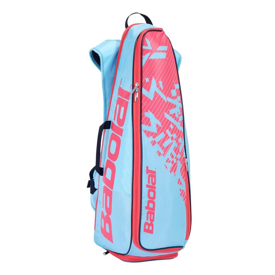 The Babolat Backracq Badminton Bag in Sky Blue and Pink is designed to stand upright and includes a zipper compartment along with backpack-style shoulder straps. The Babolat logo prominently adorns the side, while a dedicated shoe compartment offers added convenience.