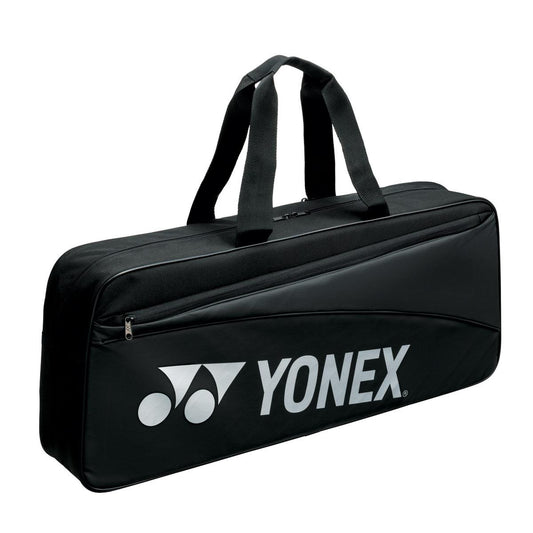 The Yonex 42331WEX Team Tournament Bag - Black is a sports bag featuring two handles and a zipper pocket. The rectangular design efficiently accommodates sports equipment, with the Yonex logo prominently displayed on the front.