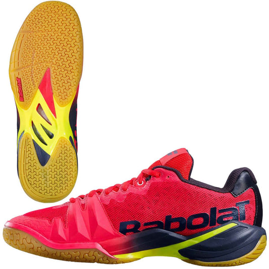 The Babolat Shadow Tour Badminton Shoes in striking red and yellow showcase a textured gum sole. A side view prominently displays the Babolat logo, while the complex sole pattern, equipped with DCS technology, provides outstanding grip.