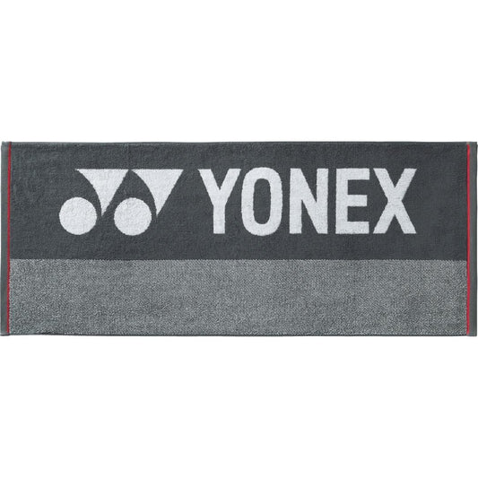 The Yonex AC1106EX Charcoal Grey Badminton Sports Towel, ideal for competitive players, showcases the iconic Yonex logo and name in white. It features a textured band at the bottom, making it a stylish addition to your racket bag.