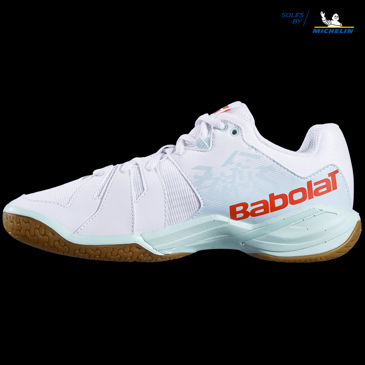 The Babolat Shadow Spirit Women's Badminton Shoes in white and light blue offer a gripsole with a gum sole, showcasing bold red "Babolat" lettering on the side. With subtle detailing and the "Soles by Michelin" marking in the top right corner, these shoes are designed for optimal performance.