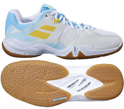 The Babolat Shadow Spirit 2023 Women's Badminton Shoes in white and light blue showcase a yellow logo on the side and feature a patterned design on the upper. With supportive gum-colored soles, these shoes are equipped with OrthoLite® Die Cut insoles for enhanced comfort. The brand name "Babolat" is prominently displayed on both the side and bottom of the shoes.