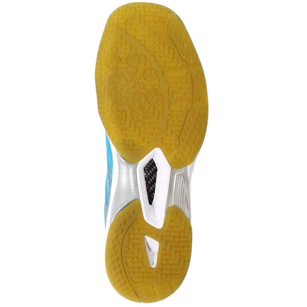 The image depicts the sole of an FZ Forza Lingus V4 Blue Badminton Shoe, featuring a non-slip yellow rubber pattern with textured detailing. The midsection showcases a small carbon fiber insert, while the heel and toe include white and blue accents, along with a reinforced toe for enhanced durability.