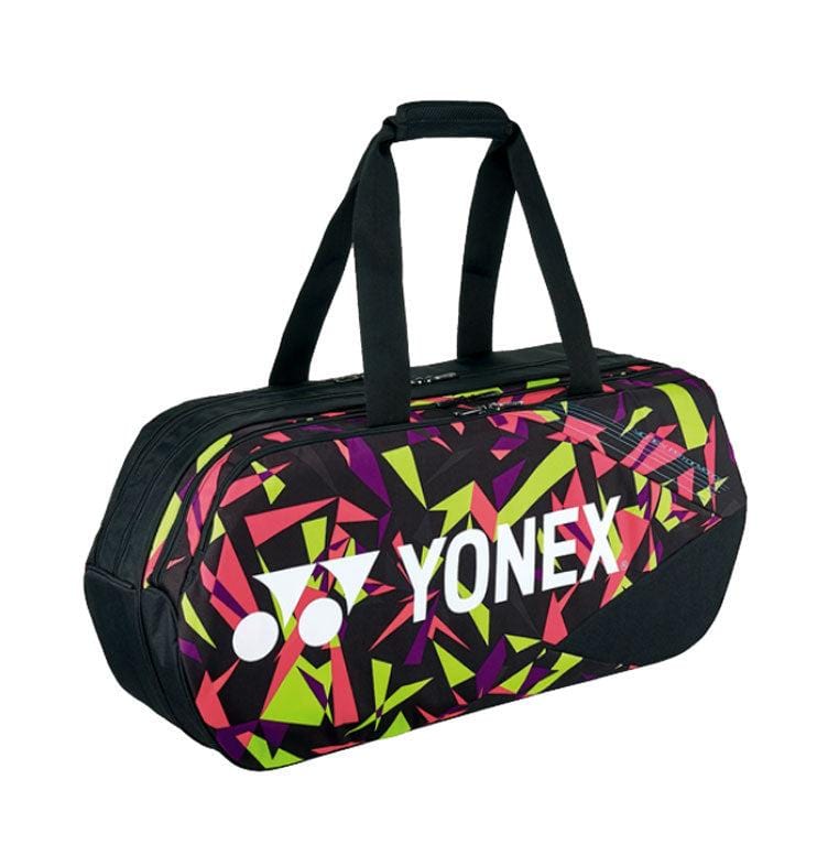 The Yonex 92231WEX Pro Tournament Bag - Smash Pink showcases a vibrant geometric design in pink, green, and yellow hues on a black background. Equipped with black handles, this professional-quality tournament-style bag is perfect for carrying sports equipment.