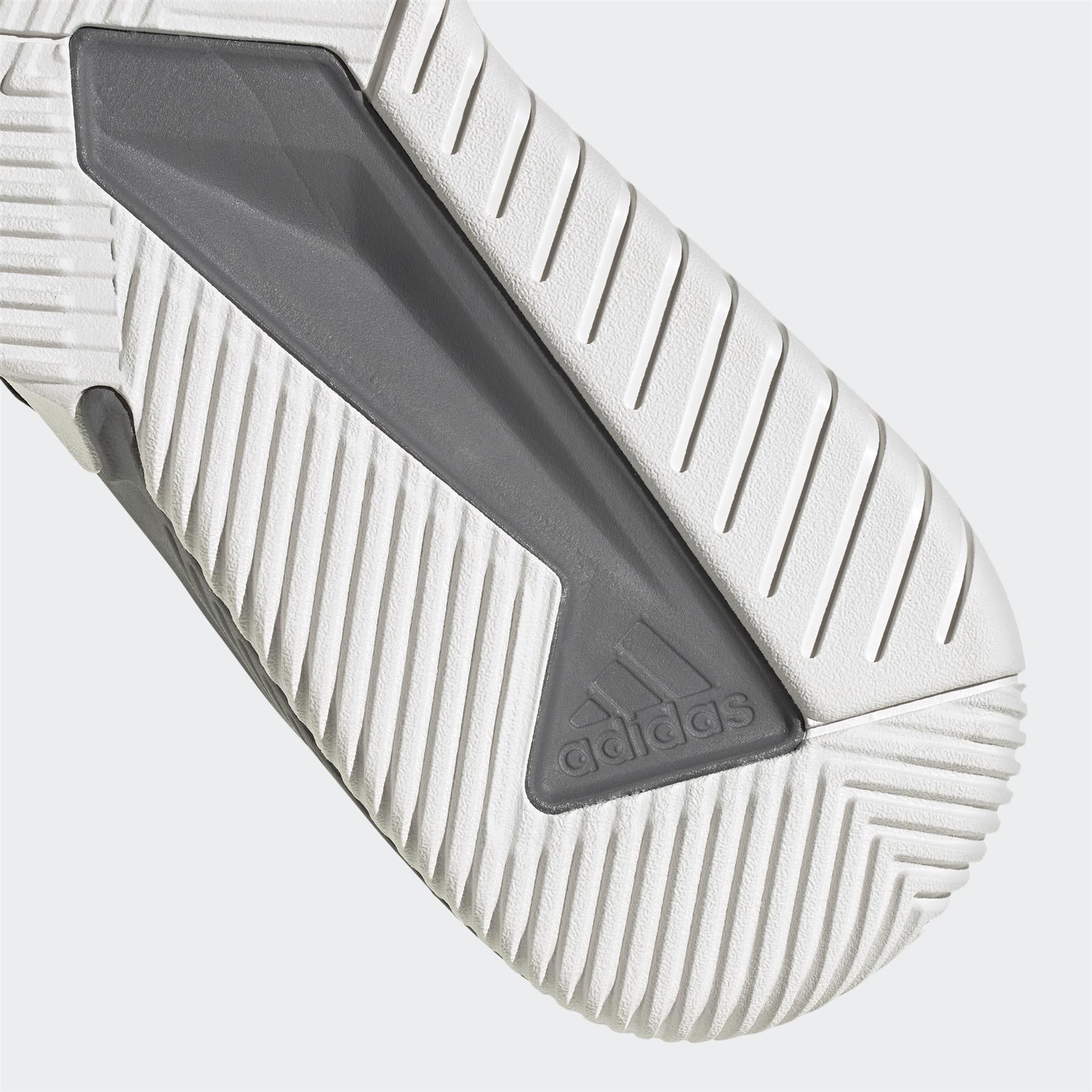 A close-up of the textured sole of the Adidas Court Team Bounce Men's Badminton Shoes in black showcases a gray triangular insert and embossed branding. The pattern features angled grooves for traction against a light gray background. Made with Primegreen recycled materials, these shoes are ideal for badminton enthusiasts.