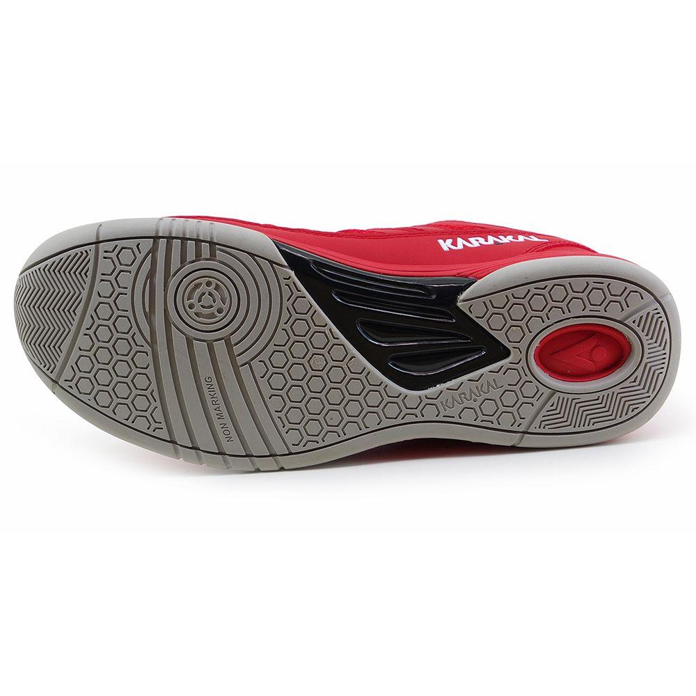 The image highlights the sole of a red and black sneaker, featuring a non-marking outsole with an intricate hexagonal tread pattern for enhanced grip. The brand name, Karakal, is visible near the heel area, offering lateral stability similar to the Karakal KF Pro Lite Mens Badminton Shoe - Red.