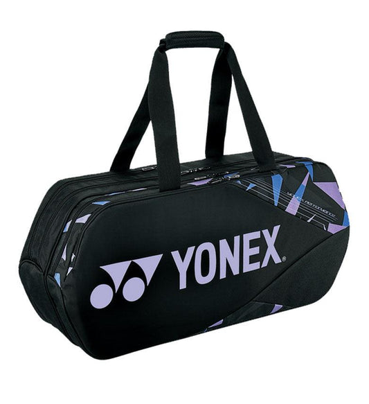 A Yonex 92231WEX Pro Tournament Bag in Mist Purple, showcasing a stylish design with purple and blue geometric accents. It features two short handles and a zippered top, with the professional quality highlighted by the prominently displayed Yonex logo on the side.