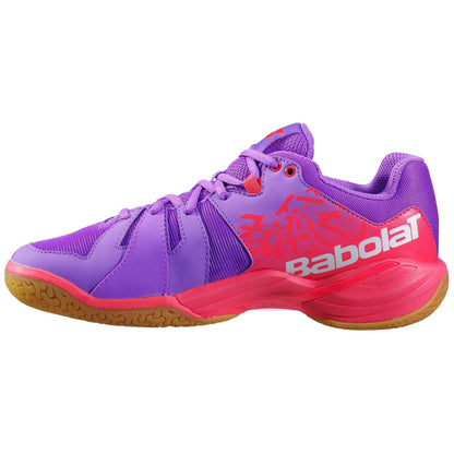 The dynamic Babolat Shadow Spirit Women's Badminton Shoes in Dewberry and Fiery Red feature a vibrant purple upper with striking red and orange accents, complemented by a tan sole crafted from durable Michelin rubber. The white "Babolat" branding adorns the side, while the shoes are equipped with laces and a low-cut design ideal for athletic pursuits.