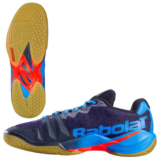 The Babolat Shadow Tour Badminton Shoes - Black Blue are athletic shoes with orange accents, featuring a textured gum sole for grip. The brand "Babolat" is prominently displayed on the side. Designed with DCS technology, they are ideal for those seeking high-performance badminton footwear.