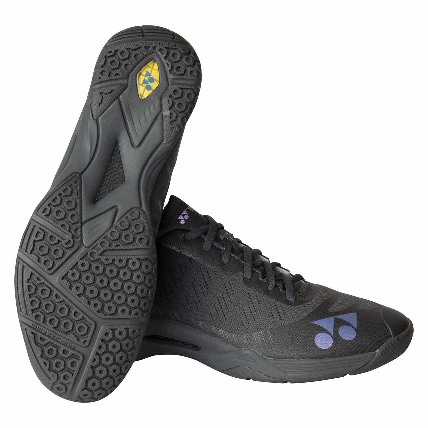 A pair of dark grey Yonex Power Cushion Aerus Z men's badminton shoes, ideal for badminton enthusiasts, with textured soles. The left shoe is positioned sole-up, showcasing the yellow logo. The right shoe prominently features a purple logo on the side. These Yonex shoes boast a sleek design and black laces.