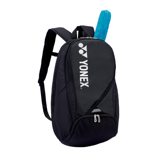 The Yonex Pro Badminton Backpack S 92212 in black is a stylish backpack that proudly displays the Yonex brand logo and name vertically on the front. It includes adjustable shoulder straps and a zippered compartment, ideal for safely storing badminton essentials, such as the blue racket handle protruding from the top.