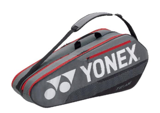 The Yonex 6 Piece Team Racket Bag 42126 LTD in Greyish Pearl boasts a durable construction with red accents, featuring a padded black shoulder strap. The Yonex logo and "TEAM" are printed in white.