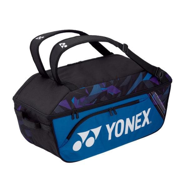 The Yonex 92214EX Pro Wide Open Racket Bag, branded by Yonex, features a logo on its side and is designed in fine blue and black. This spacious racket bag includes two black carrying handles, a zippered front pocket, and sports a geometric pattern on its top section.