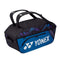 The Yonex 92214EX Pro Wide Open Racket Bag, branded by Yonex, features a logo on its side and is designed in fine blue and black. This spacious racket bag includes two black carrying handles, a zippered front pocket, and sports a geometric pattern on its top section.