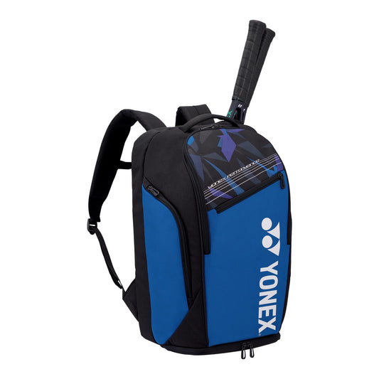 A Fine Blue Yonex Pro Badminton Backpack L 92212 with a tennis racket handle protruding from the top compartment. This adaptable backpack, from the Yonex brand, includes adjustable shoulder straps, a dedicated shoe compartment, and prominently displays the Yonex logo on the front.