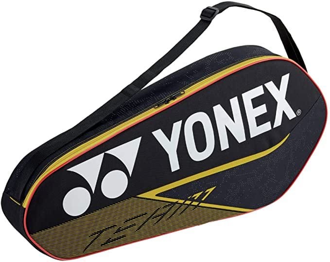 The Yonex 42023EX Team 3 Piece Badminton Racket Bag, perfect for avid players who travel light, showcases a sleek black design highlighted by a prominent white logo and yellow accents. It ensures convenience with its shoulder strap and secure zippered closure.