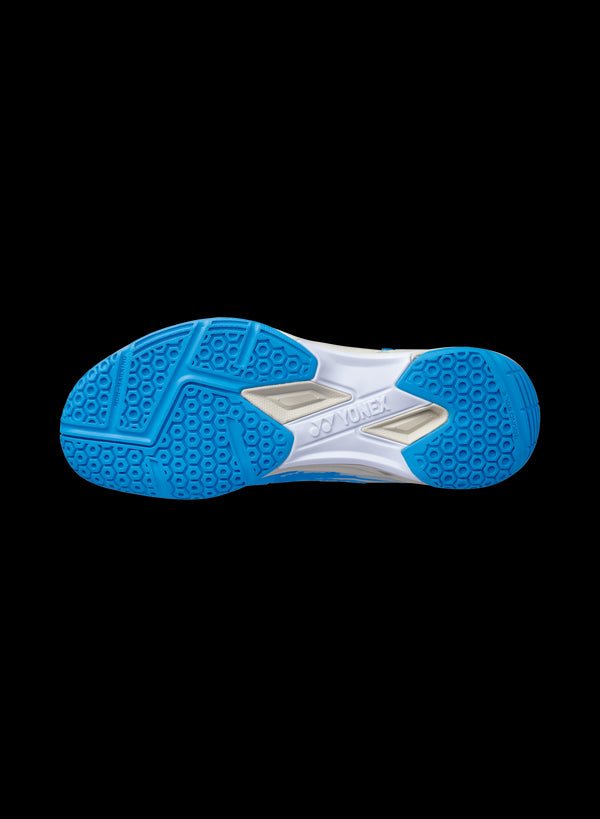 The image features the sole of a Yonex Power Cushion Cascade Drive Badminton Shoe in Ocean Blue, showcasing textured patterns for grip and outstanding shock absorption. The word "Yonex" stands out in white, clearly indicating the shoe's brand. A plain black background enhances the contrast.