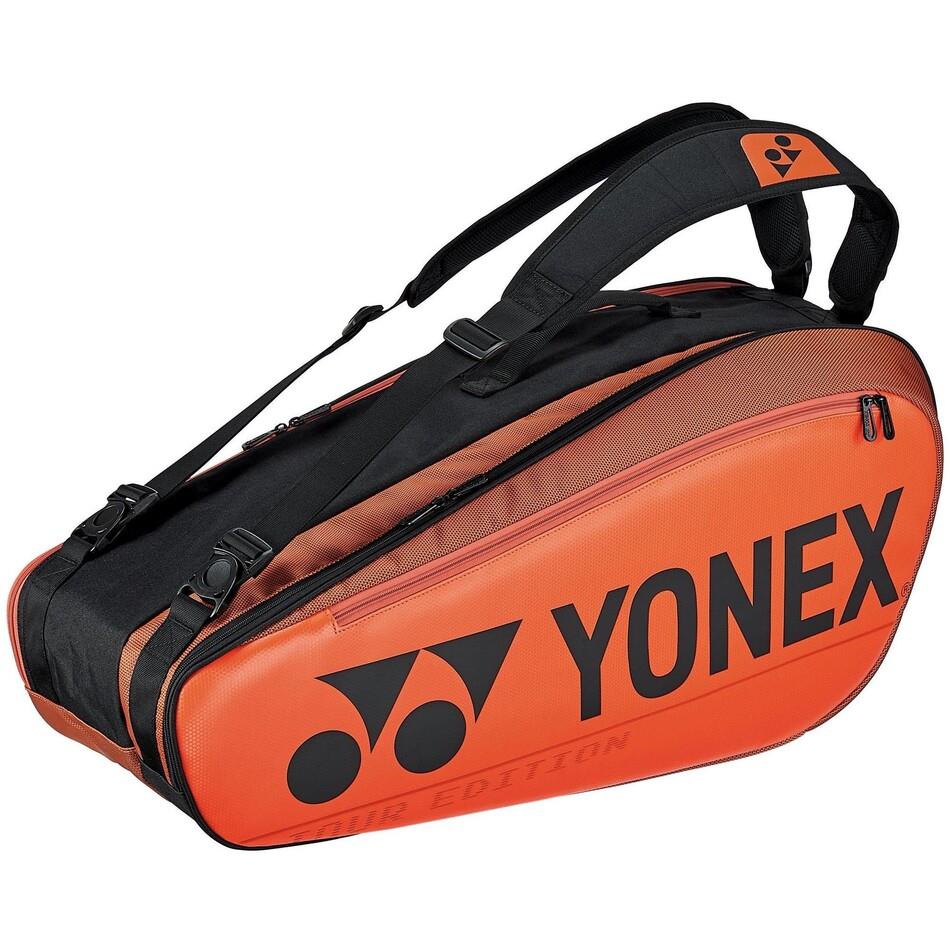 The Yonex 92026EX Pro 6 Piece Badminton Racket Bag in copper orange and black is designed to hold up to six rackets. It boasts a spacious compartment, shoulder straps for easy carrying, and the Yonex logo along with "Tour Edition" inscribed on its side. Additionally, it includes a handy shoe compartment for storing your gear.