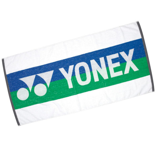 The Yonex AC705WEX White Badminton Bath Towel, with dimensions of 60 x 120 cm, showcases a sleek white backdrop adorned with vibrant blue and green stripes. The Yonex brand logo and name are elegantly featured in white on the blue stripe, offering a combination of style and practicality for all your sporting requirements.