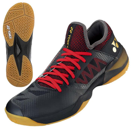 Introducing the Yonex Power Cushion Comfort Z2 Men's Badminton Shoes in a sleek Black/Red design, featuring striking red laces. These shoes offer outstanding impact protection and traction, thanks to their honeycomb-patterned gum sole. One shoe is presented from a side view, highlighting its stylish profile, while the other showcases the effective sole design.