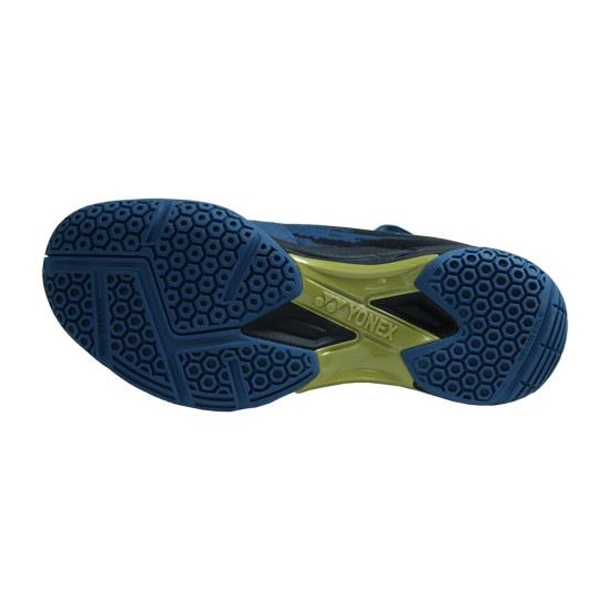 The image displays the sole of the Yonex Power Cushion Cascade Drive Badminton Shoes in Teal Blue, showcasing a blue hexagonal tread pattern and a green central support accented with the Yonex logo. This design incorporates Yonex's renowned Power Cushion technology to enhance grip, stability, and offer superior shock absorption.