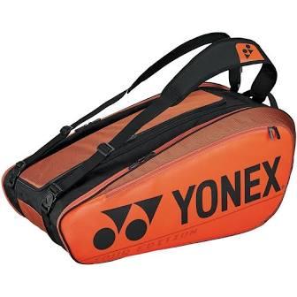 The Yonex 92029EX Pro 9 Piece Badminton Racket Bag in copper orange boasts shoulder straps and displays a prominent logo on the side. It is made with isothermal material, ensuring that it carries rackets and other tennis essentials while maintaining an optimal temperature.